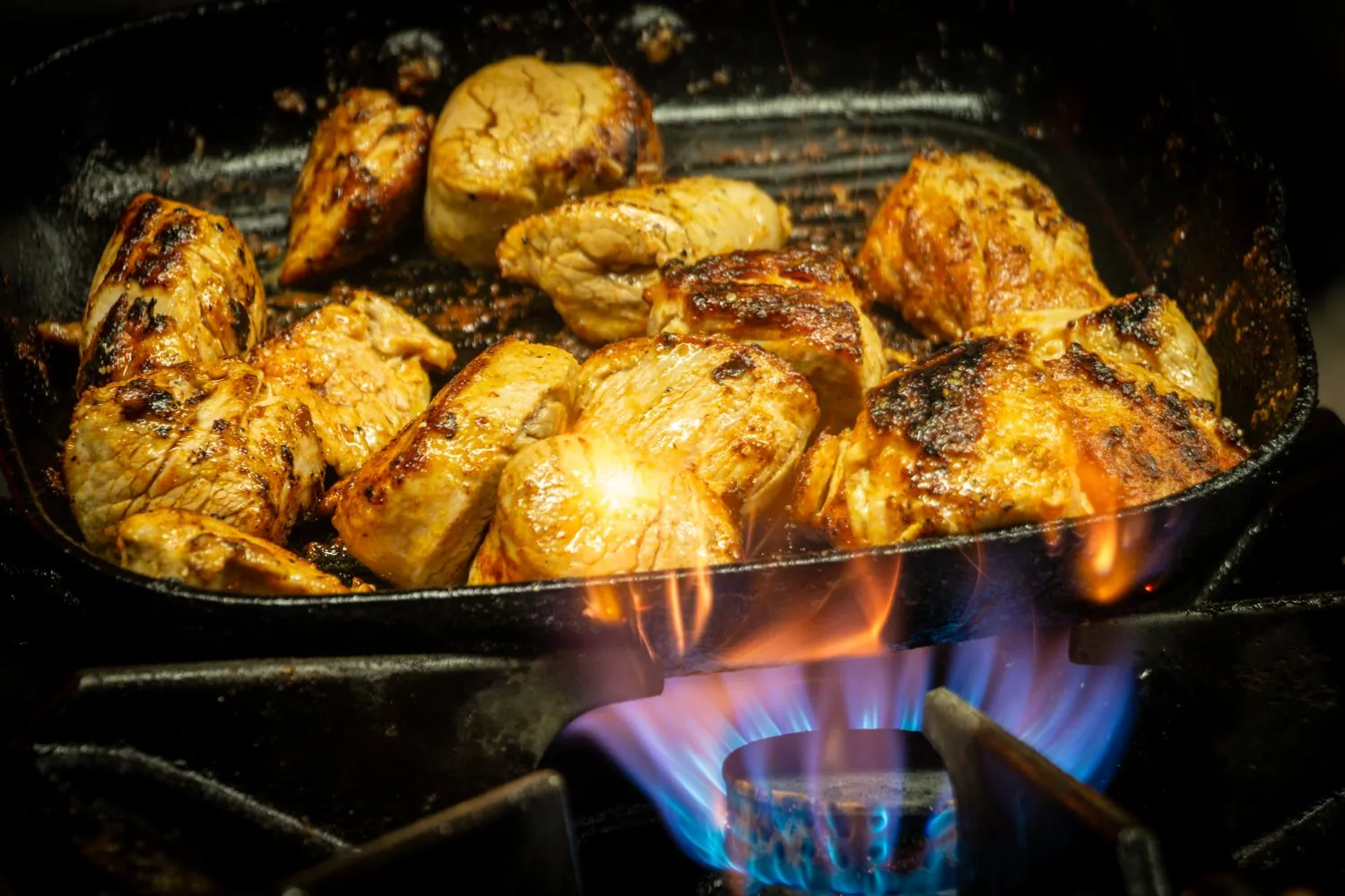 Gegrilltes Fleisch in der Gusseisenpfanne über offener Flamme
