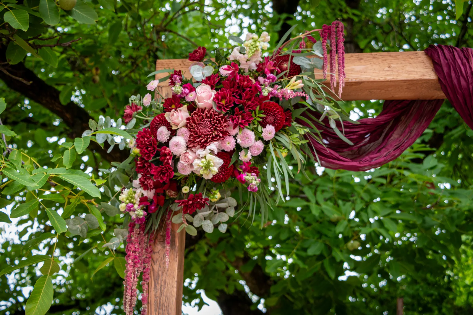 Blumengesteck in Rot und Rosa am Traubogen